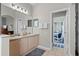 Bright bathroom featuring double sinks, a well-lit mirror, and a doorway to another room at 2222 Wyndham Palms Way, Kissimmee, FL 34747