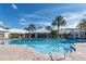Resort-style pool and clubhouse with ample lounge chairs under a sunny blue sky, surrounded by lush palm trees at 2222 Wyndham Palms Way, Kissimmee, FL 34747