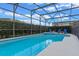 Screened-in pool area with a heated pool, lush landscaping, and lounge chairs at 2222 Wyndham Palms Way, Kissimmee, FL 34747