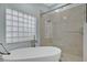 Luxurious bathroom featuring soaking tub, a glass shower with marble tiles and a unique glass block window at 2250 Blossomwood Dr, Oviedo, FL 32765