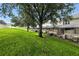 Large backyard view showcasing lush lawn and screened-in patio area with mature trees at 2409 Silver Palm Dr, Kissimmee, FL 34747