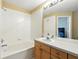 Well-lit bathroom showing a bathtub and shower, a white tiled wall, and a wood vanity at 2409 Silver Palm Dr, Kissimmee, FL 34747