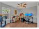 Well-lit office featuring hardwood floors, a ceiling fan, desk with two monitors, and shelves stocked with books and games at 2935 Canoe Cir, St Cloud, FL 34772