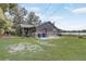 View of the home's exterior featuring a stone facade, red door, and a lovely lakeside view at 369 Bluff Lake Rd, Mascotte, FL 34753