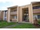 Beige two-story condo building with a staircase leading to the second-floor units, surrounded by green grass and landscaping at 5027 Vineland Rd # 5027, Orlando, FL 32811