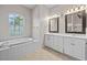 Bathroom featuring double vanity sinks, tile flooring, and soaking tub at 5339 Pond Crossing Pl, Leesburg, FL 34748