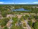 An aerial shot showcases a serene pond alongside train tracks, homes, and vegetation, beneath a clear sky at 604 Thrush Ave, Longwood, FL 32750
