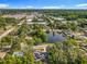 Aerial view of a community featuring lush trees, with a serene pond, nearby commercial buildings and a clear sky above at 604 Thrush Ave, Longwood, FL 32750