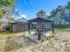 View of the backyard featuring a cozy gazebo, shed, and a home with solar panels under a sunny blue sky at 604 Thrush Ave, Longwood, FL 32750