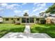 Beautiful backyard with green lawn, screened patio, and a quaint yellow house on a sunny day at 692 Gaslight Dr, South Daytona, FL 32119