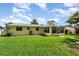 Charming backyard with green lawn, screened patio, and a yellow house in a tranquil setting at 692 Gaslight Dr, South Daytona, FL 32119