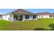 Exterior view of back of home with covered patio and green grass at 7161 Sw 135Th Pl, Ocala, FL 34473