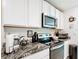 Kitchen showcasing granite countertops, a range of appliances, and white cabinets at 7161 Sw 135Th Pl, Ocala, FL 34473