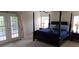 Well-lit bedroom with a four-poster bed, bedside tables, and balcony access through glass doors at 844 Suffolk Pl, Davenport, FL 33896