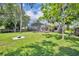 Large, grassy backyard with mature trees, patio, and screened in pool area at 1181 Pine Ln, St Cloud, FL 34771