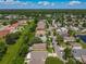 Residential neighborhood aerial showcasing tree-lined streets and various single-Gathering homes, with a pond and green spaces in the distance at 12938 Maribou Cir, Orlando, FL 32828