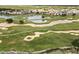 A serene aerial view of a golf course with sand traps, a lake, bridge, and meticulously maintained green fairways at 1409 Bellamy Dr, Reunion, FL 34747