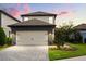 Two-story home with a neutral color palette, stone accents, and a two-car garage, complemented by lush landscaping at 1409 Bellamy Dr, Reunion, FL 34747