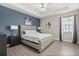 Comfortable main bedroom featuring a queen-size bed, a ceiling fan, and a soothing blue accent wall at 1409 Bellamy Dr, Reunion, FL 34747