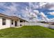 Backyard featuring green lawn, covered patio area, and enclosed white fence at 165 Lavenna Ave, St Cloud, FL 34771