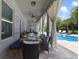 Outdoor dining area with long table and seating with pool view and elegant curtains at 17551 Black Rail St, Windermere, FL 34786