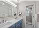 Bright bathroom featuring dual sinks, a large mirror, blue cabinets, and a walk-in shower at 264 Agnes Ave, Longwood, FL 32750