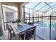 A screened-in covered patio includes a dining table set with a view of the pool area at 2665 Petition Ln, Kissimmee, FL 34746