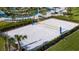 Aerial view of a pristine white sand volleyball court with blue net posts, surrounded by lush greenery and community amenities at 2665 Petition Ln, Kissimmee, FL 34746