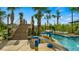 Charming water feature with stone accents and play structures next to a lazy river, surrounded by lush tropical landscaping at 2665 Petition Ln, Kissimmee, FL 34746