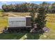 The welcoming sign to Lake Denham Estates is surrounded by landscaping and trees at 3408 Curlew Ave, Leesburg, FL 34748