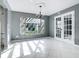 Dining room with modern chandelier, white tiled floors, and a large window showcasing backyard pergola at 3417 Pershing Ave, Orlando, FL 32812