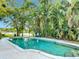 Large pool surrounded by lush landscaping with water views beyond at 3417 Pershing Ave, Orlando, FL 32812