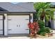A white two-car garage door with decorative hardware and colorful landscaping at 533 Quail Down Dr, Debary, FL 32713