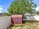 Backyard view of a shed surrounded by a white vinyl fence and green vegetation at 5409 Holtland Dr, Apopka, FL 32712