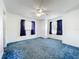 Bedroom with blue carpet, ceiling fan, two windows with blue curtains and an ensuite door at 5409 Holtland Dr, Apopka, FL 32712