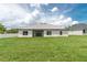 Backyard view featuring a well-maintained lawn and the home's rear elevation, including windows and a patio door at 5908 Sw 115 Street Rd, Ocala, FL 34476