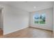 Minimalist bedroom with wood floor, white walls, and large window looking out to greenery at 5908 Sw 115 Street Rd, Ocala, FL 34476