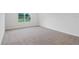 Neutral-toned bedroom with carpeted floors and a large window overlooking the backyard at 5908 Sw 115 Street Rd, Ocala, FL 34476