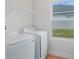 Bright laundry area featuring modern white appliances, a convenient overhead shelf, and a well-lit window at 5908 Sw 115 Street Rd, Ocala, FL 34476