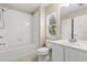 Well-lit bathroom with white tile, single vanity and window, with a combined shower and bathtub at 6874 Slaven Dr, Orlando, FL 32819