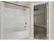 Clean bathroom featuring a tub and shower combo, with white tile, a neutral color scheme and a glimpse of an adjacent bedroom at 6874 Slaven Dr, Orlando, FL 32819