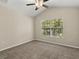 A spacious bedroom with neutral carpet, ceiling fan, and a window offering natural light at 6874 Slaven Dr, Orlando, FL 32819