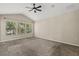A sunlit bedroom has carpet flooring and three windows with views of lush greenery outside at 6874 Slaven Dr, Orlando, FL 32819
