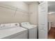 Bright laundry room with white washer and dryer, wire shelving, and access to the stairs at 6874 Slaven Dr, Orlando, FL 32819