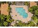 Aerial view of a community pool with chairs and umbrellas on decorative paving stones plus mature trees at 6874 Slaven Dr, Orlando, FL 32819