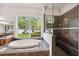Bathroom featuring a soaking tub with shower and a large window overlooking the backyard at 748 Mills Estate Pl, Chuluota, FL 32766