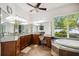 Bathroom featuring multiple sinks, granite countertops, large mirrors, and a soaking tub with a backyard view at 748 Mills Estate Pl, Chuluota, FL 32766