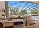 Outdoor kitchen with stone countertops, a built-in grill, and sink overlooking the screened pool at 748 Mills Estate Pl, Chuluota, FL 32766