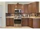 The kitchen features stainless steel appliances, brown cabinets, and granite countertops at 930 Willow Oak Loop, Minneola, FL 34715