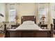 Luxurious main bedroom boasts a dark wood bed set and windows dressed with white curtains at 930 Willow Oak Loop, Minneola, FL 34715